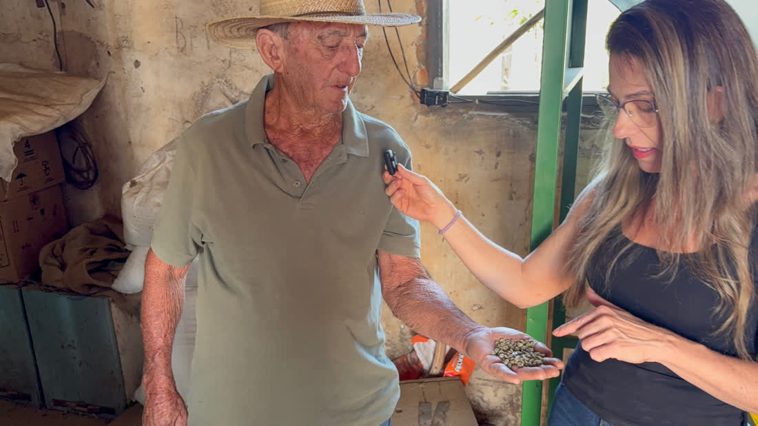 Sr. David mostrando os grãos na mão para a Juliana
